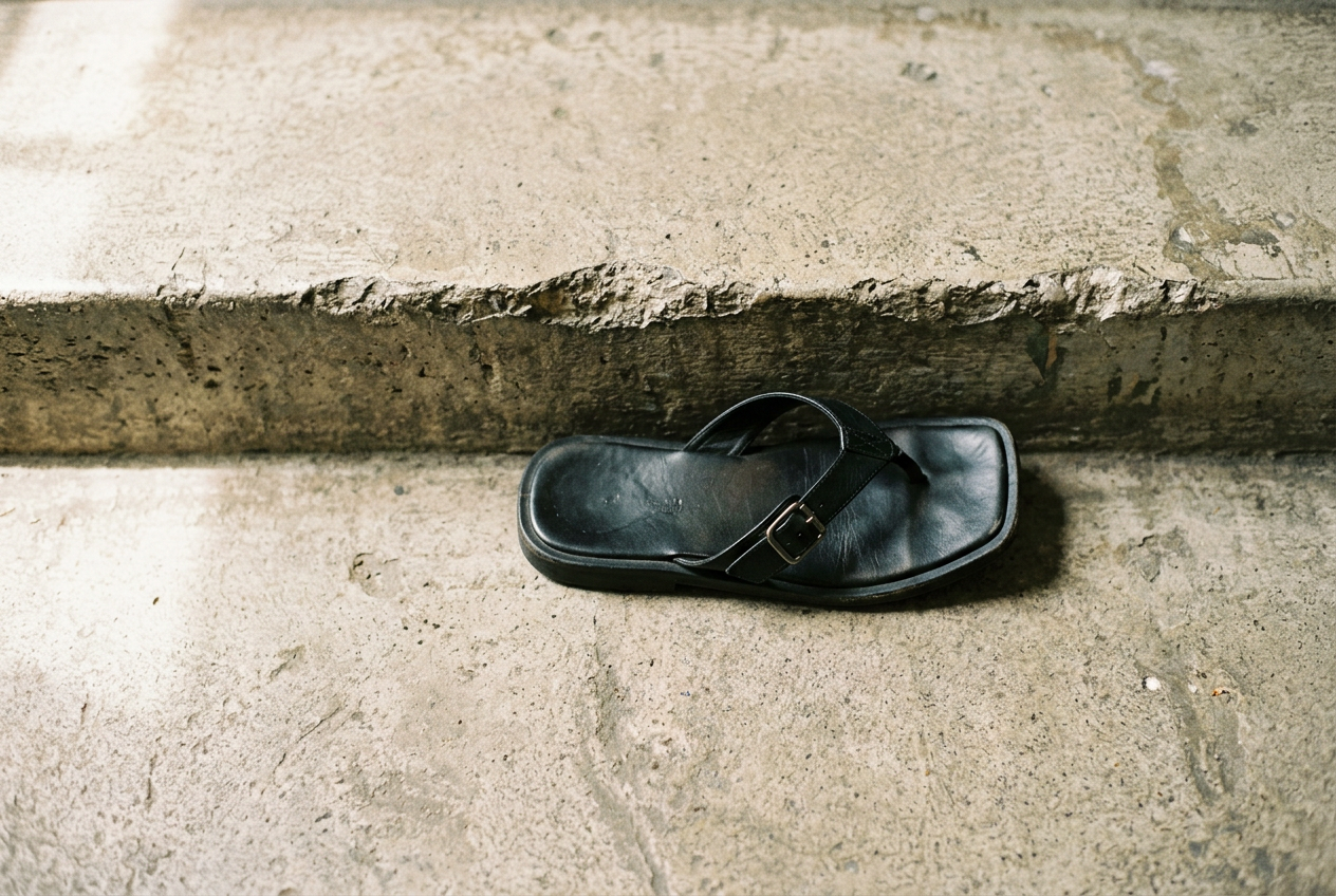 Square toe flip flops positioned beside a stair edge, showing the unsupported outer corner of each sole.