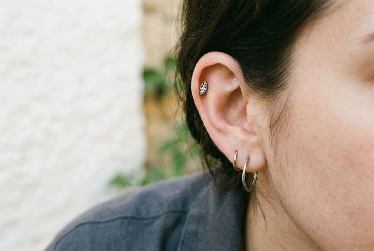 Close view of a marquise flat back stud sitting diagonally above a small hoop in a second-lobe piercing.